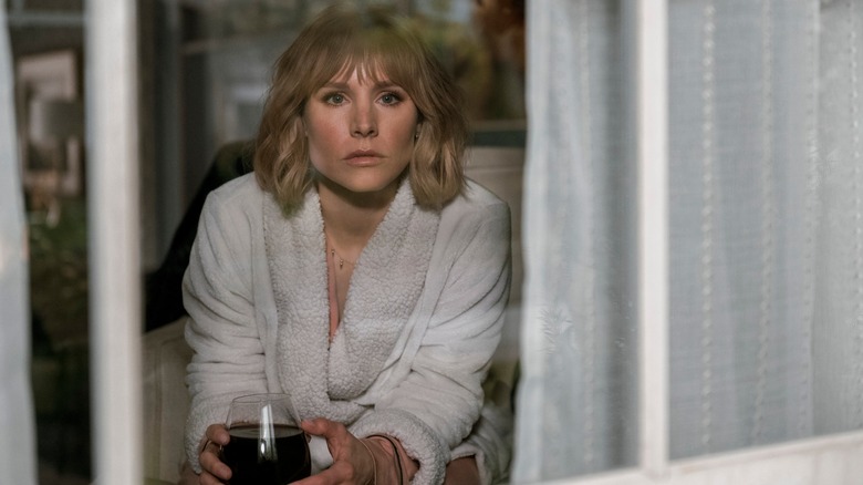 Anna sitting in a window with a huge glass of wine in The Woman in the House Across the Street From The Girl In The Window