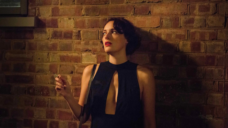 Fleabag in a black low cut jumpsuit smoking a cigarette in Fleabag