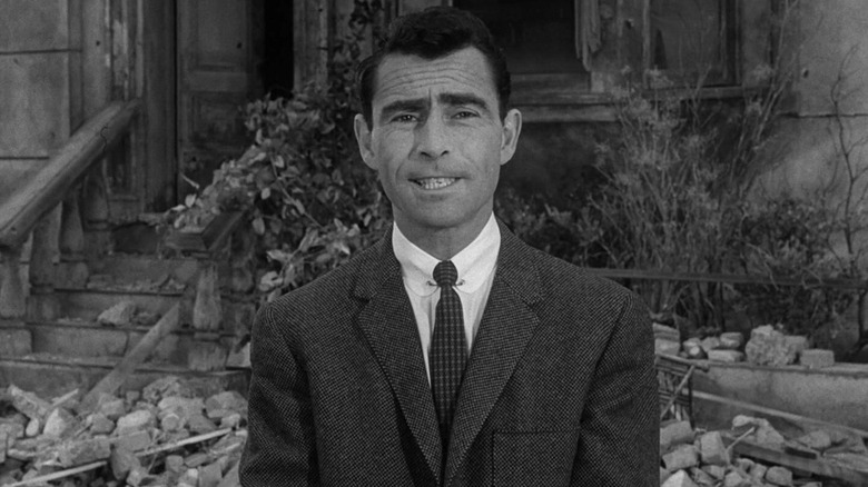 Rod Serling standingin front of a ruined house on The Twilight Zone