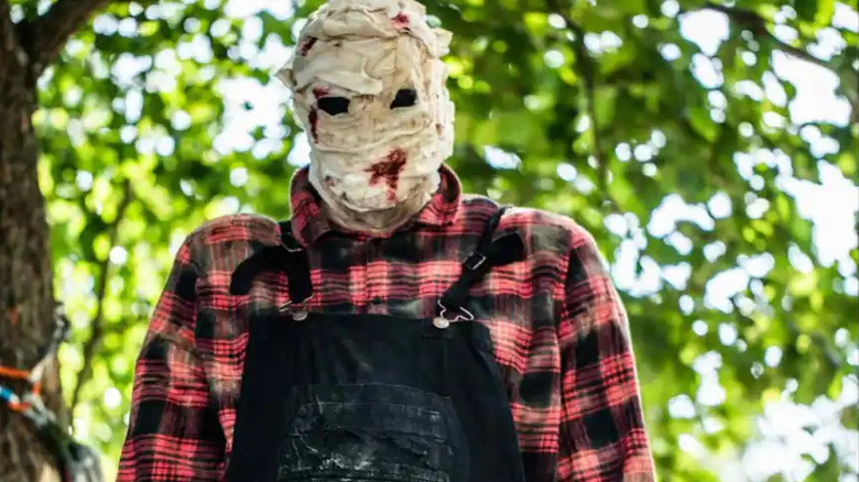 The Handyman stands in the woods in Killer Camp