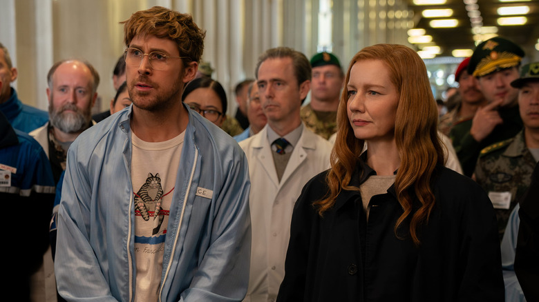 Ryland and Eva standing in front of scientists in Project Hail Mary