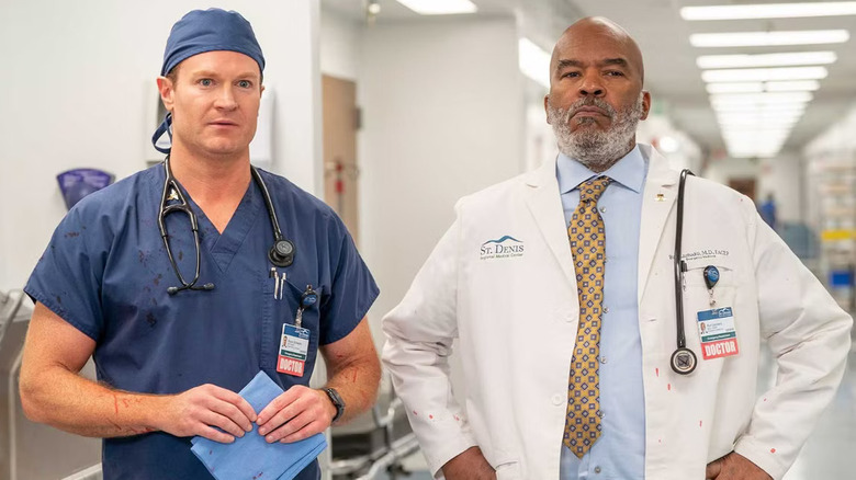 Emergency surgeon, Bruce, and ER Attending, Ron, standing in the hospital side-by-side in workwear
