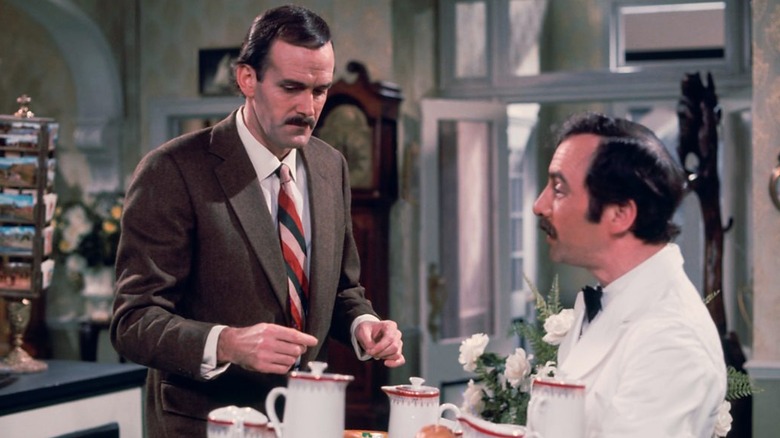 Basil looking at a tray being held by Manuel in Fawlty Towers (1975)