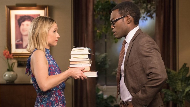 Eleanor handing a stack of books to Chidi in The Good Place (2016)