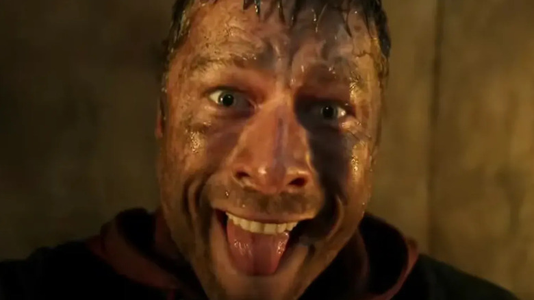A bedraggled Ben Richards sticking his tongue out in "The Running Man" (2025)
