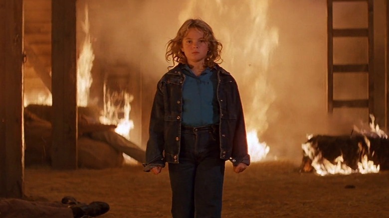Charlie McGee standing in front of a burning building in "Firestarter"