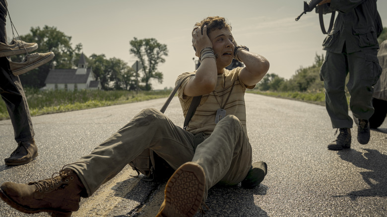 Curly crying on the ground being approached by a soldier in "The Long Walk" (2025)