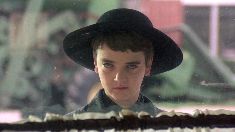 Creepy child in a black hat staring through the window in Children of the Corn
