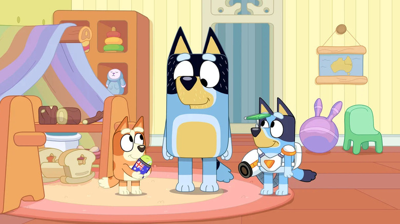 Bluey and Bingo stand on either side of their dad in "Bluey"