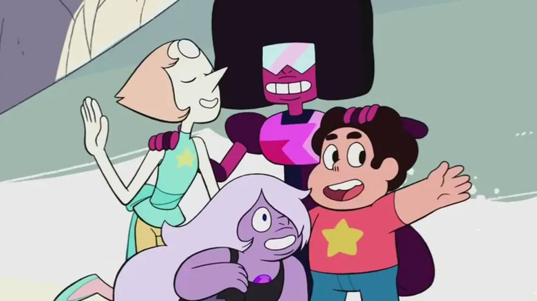 Pearl, Garnet, Steven, and Amethyst embrace with smiles on their faces in "Steven Universe"