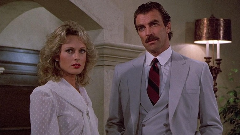 Magnum in a grey suit standing near Cindy in Magnum, P.I. (1980)