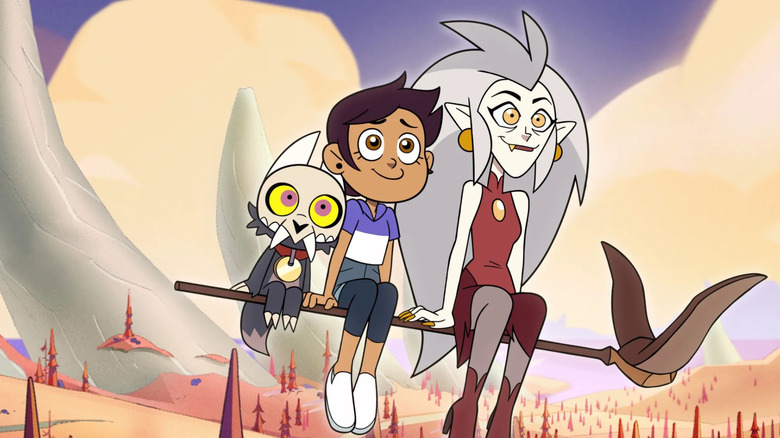 Eda, Luz, and King sitting on a flying broomstick and smiling as they look into the distance in The Owl House (2020)