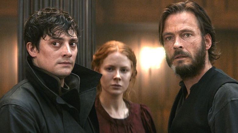 Emily Beecham standing between two other passengers aboard the Kerberos steamship in 1899 (2022)