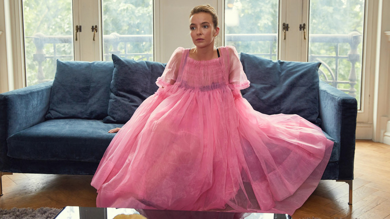 Villanelle in a pink dress sitting on a couch in Killing Eve