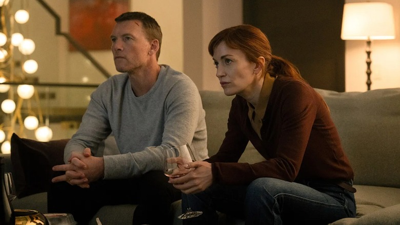 David and Rachel leaning forward on a couch watching something on I Will Find You