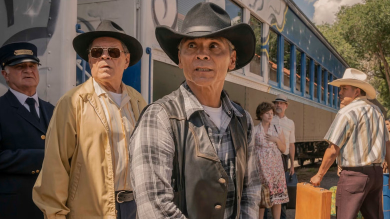 Leaphorn standing near a train next to another deputy in "Dark Winds" (2022-present)