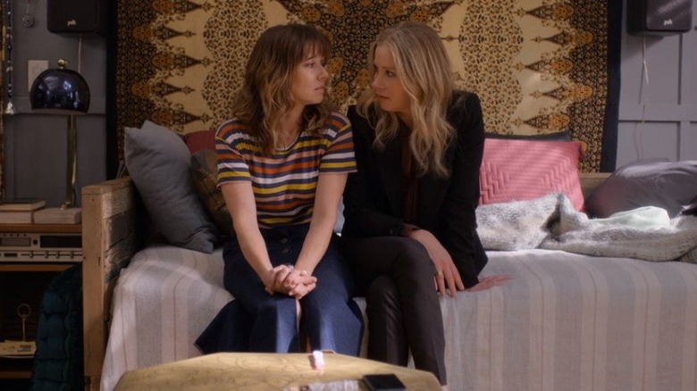 Judy and Jen sit on a bed and look at one another in Dead to Me