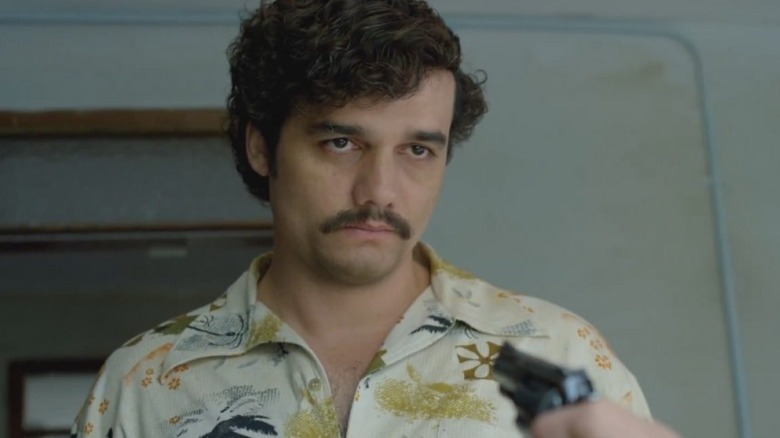 A hand pointing a gun at Pablo Escobar in Narcos (2015)