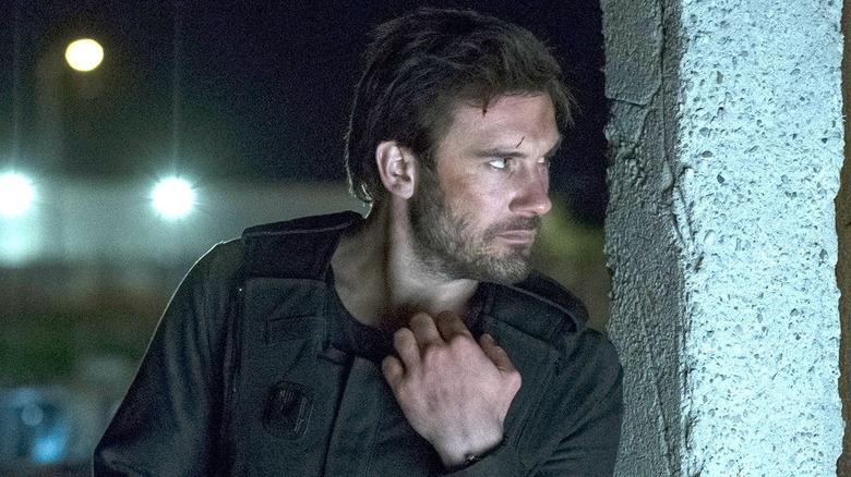 Mills hiding behind a pillar in Taken (2017)