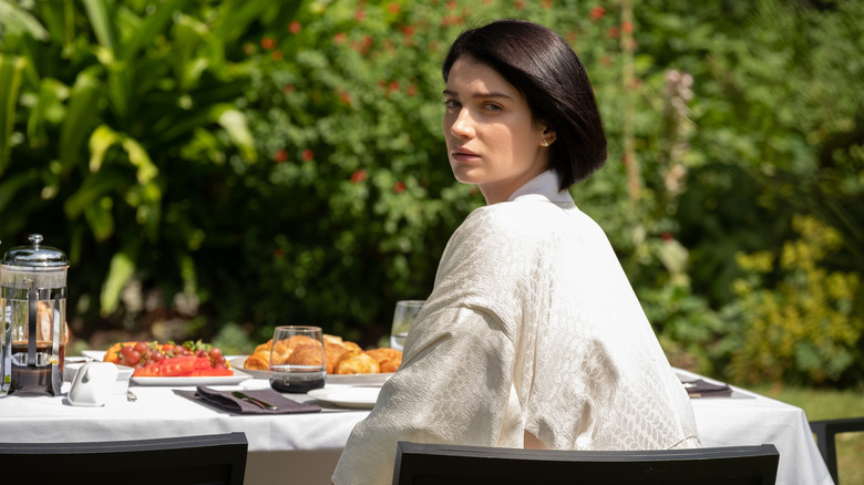 Adele at a table looking over her shoulder on Behind Her Eyes