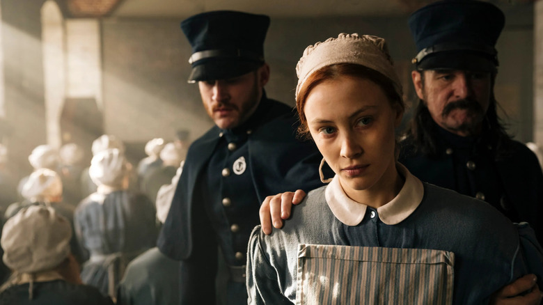 Grace with two police officers behind her on Alias Grace