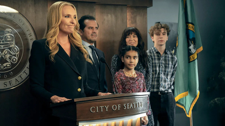 Margot giving a press conference with Rob and Jos behind her on The Power