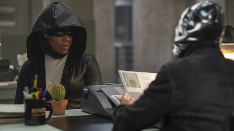 Sister Night sitting across from a masked man in Watchmen