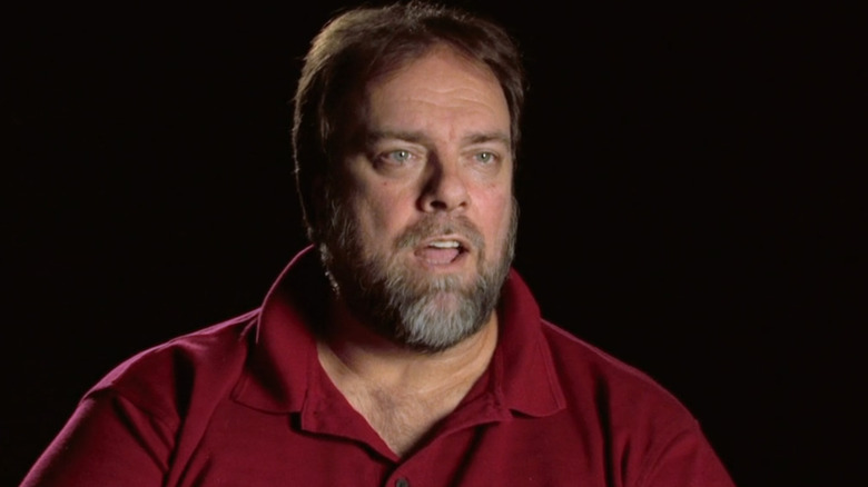 Mark in a red polo shirt in front of a black background from "I Survived..." (2008-2015)