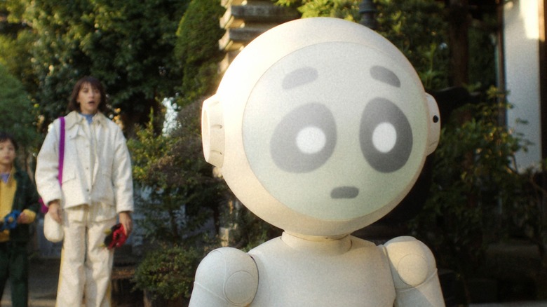 Sunny the domestic assistance robot walking ahead of Suzie in Sunny (2024)