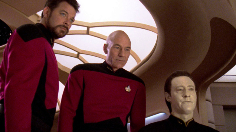 Riker, Picard, and Data study a display screen in 
