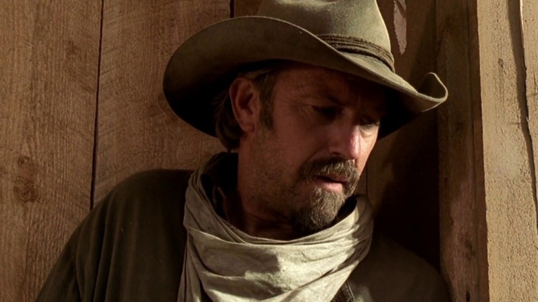 Charley (Kevin Costner) leaning against a wooden wall in "Open Range."