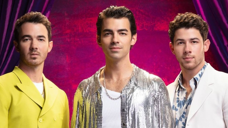 Nick, Joe, and Kevin Jonas beside curtains on 
