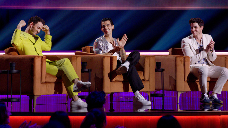 Kevin Jonas, Nick Jonas, and Joe Jonas sitting in chairs at the "Jonas Brothers Family Roast" (2021)