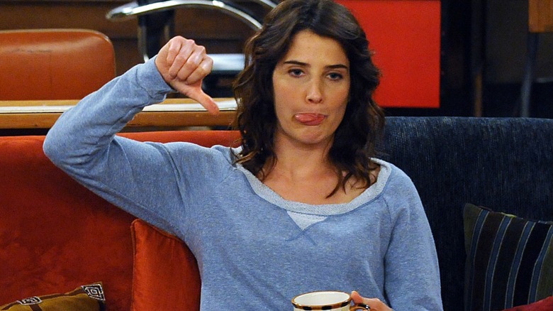 Robin blowing a raspberry and giving a thumbs down on the couch in How I Met Your Mother