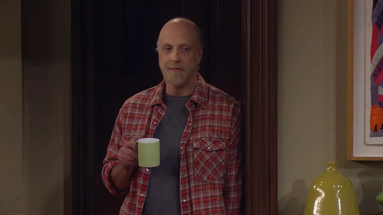 Mickey holding a coffee cup in a doorway wearing a flannel shirt on How I Met Your Mother