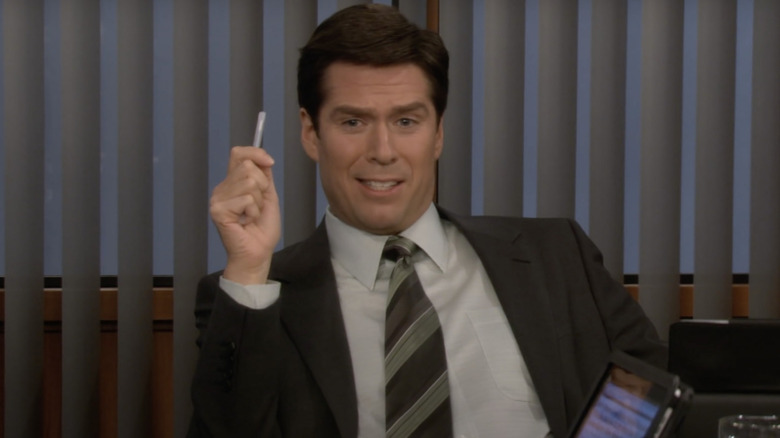 Sandy holding a pen in a meeting in a suit and tie on How I Met Your Mother