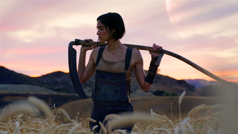 Kora holding scythe in a field in Rebel Moon (2023)