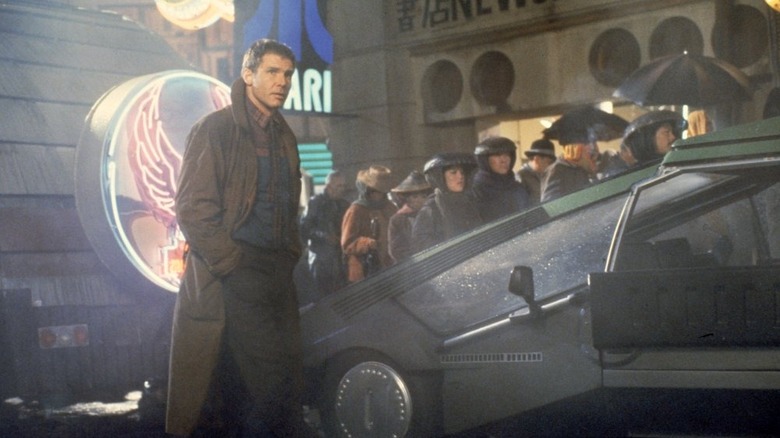 Rick walking through the city next to a car in Blade Runner