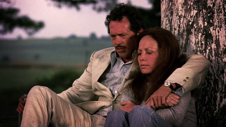 Bennie and Elita sitting by a tree in Bring Me The Head of Alfredo Garcia (1974)
