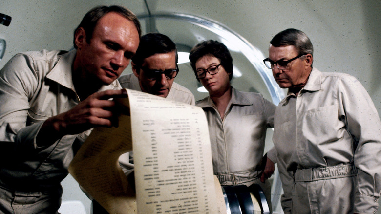 Dr. Hall, Dr. Stone, Dr. Leavitt, and Dr. Dutton looking over document in The Andromeda Strain