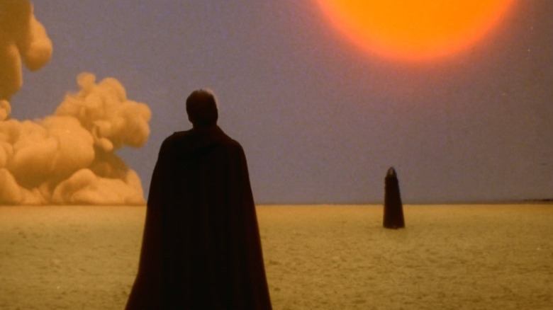 Cloaked figures facing each other in the desert in The Visitor