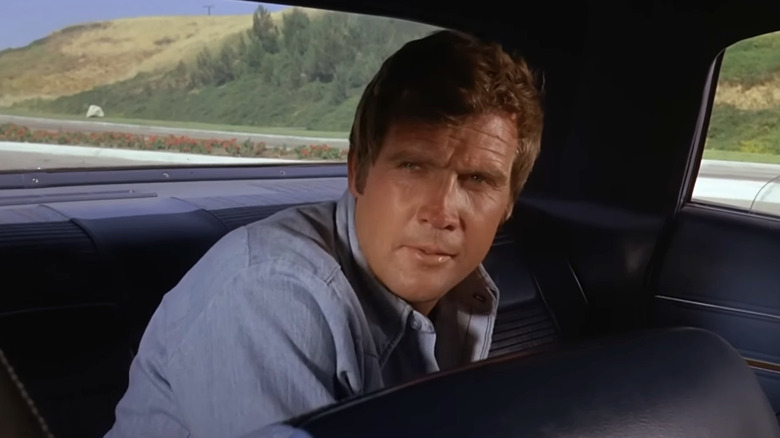 Steve Austin sitting in the backseat of a car in "The Six Million Dollar Man"