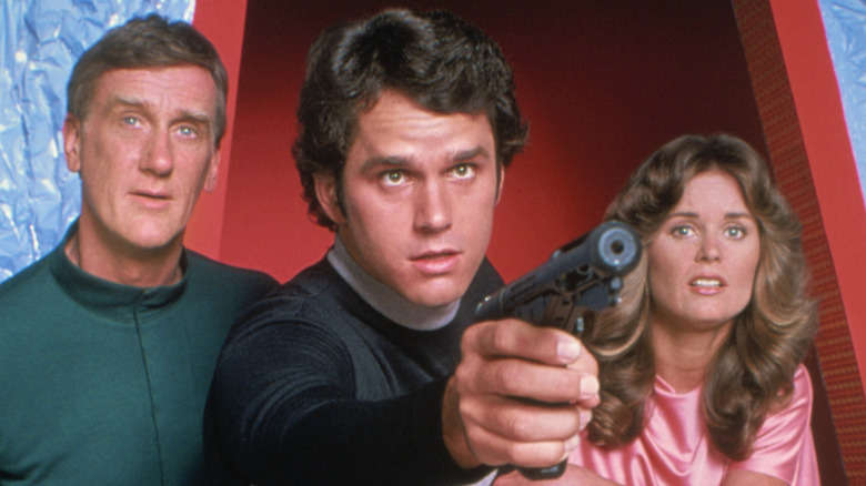 Rem and Jessica 6 look on as Logan 5 points a gun in Logan's Run (1977)