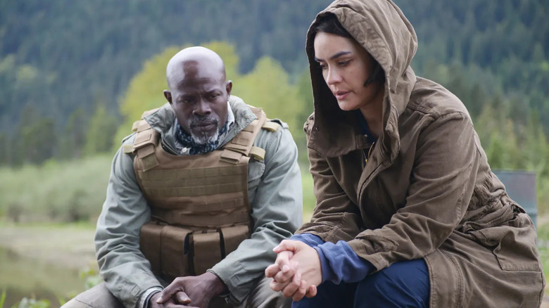 CJ (Djimon Hounsou) and Theresa (Shannyn Sossamon) sitting together in front of a woodsy landscape in post-apocalyptic Idaho