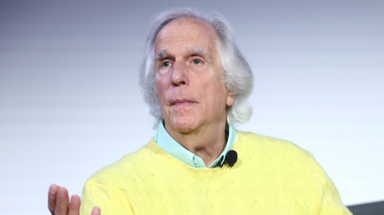 Henry Winkler sitting on stage gestering