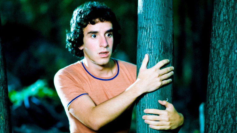 Alfred looking horrified and holding onto a tree in a dark forest in "The Burning" (1981)