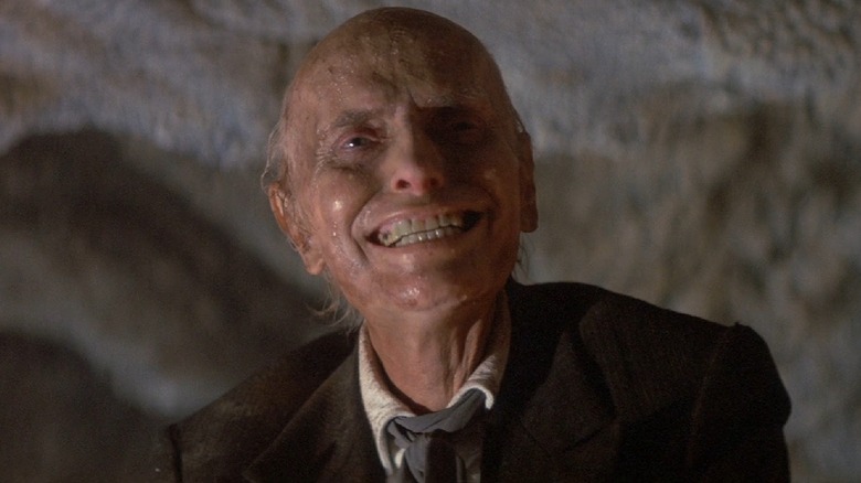 Kane grins maniacally in a cave in 