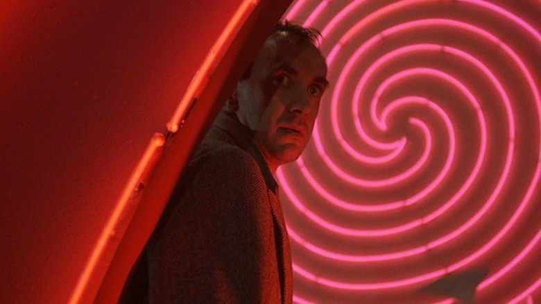 Sam Lowry standing by swirly light fixture in 'Brazil' (1985)