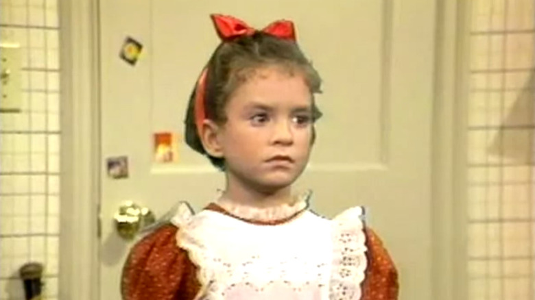 Android girl Vicki stands with a blank stare in a kitchen in Small Wonder.