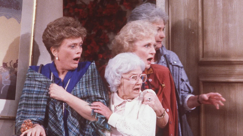 Blanche Devereaux, Sofia Petrillo, Rose Nylund, and Dorothy Zbornak all stand in shock in a doorway in The Golden Girls.